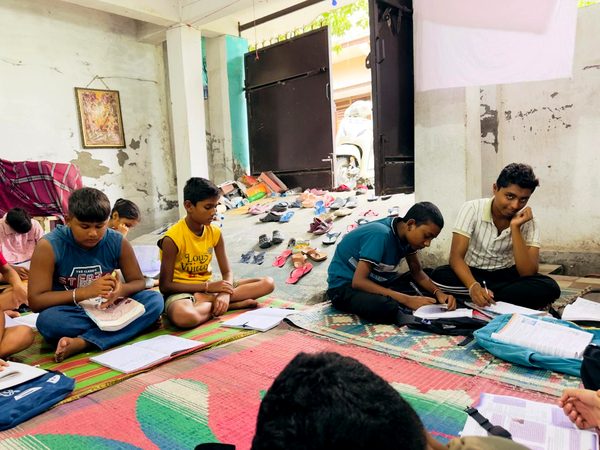 Students doing schoolwork on the floor mats at the centre